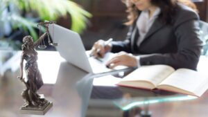 Statue of Justice with Scales and a Woman Lawyer Working on a Laptop