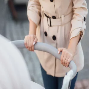 Woman holding both hands on a baby stroller.