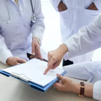 Doctors discussing subjects from a document.