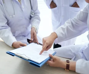 Doctors discussing subjects from a document.