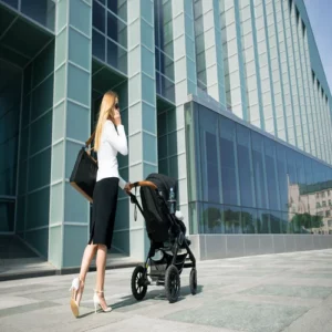 Mother walks with the baby stroller near a building